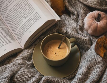 Tasse de café sur un lit avec un livre sur un plaid