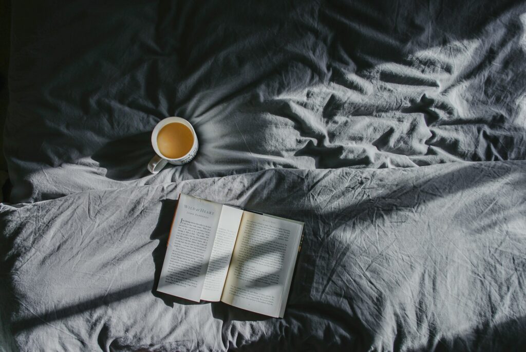 Tasse de café et livre sur un lit