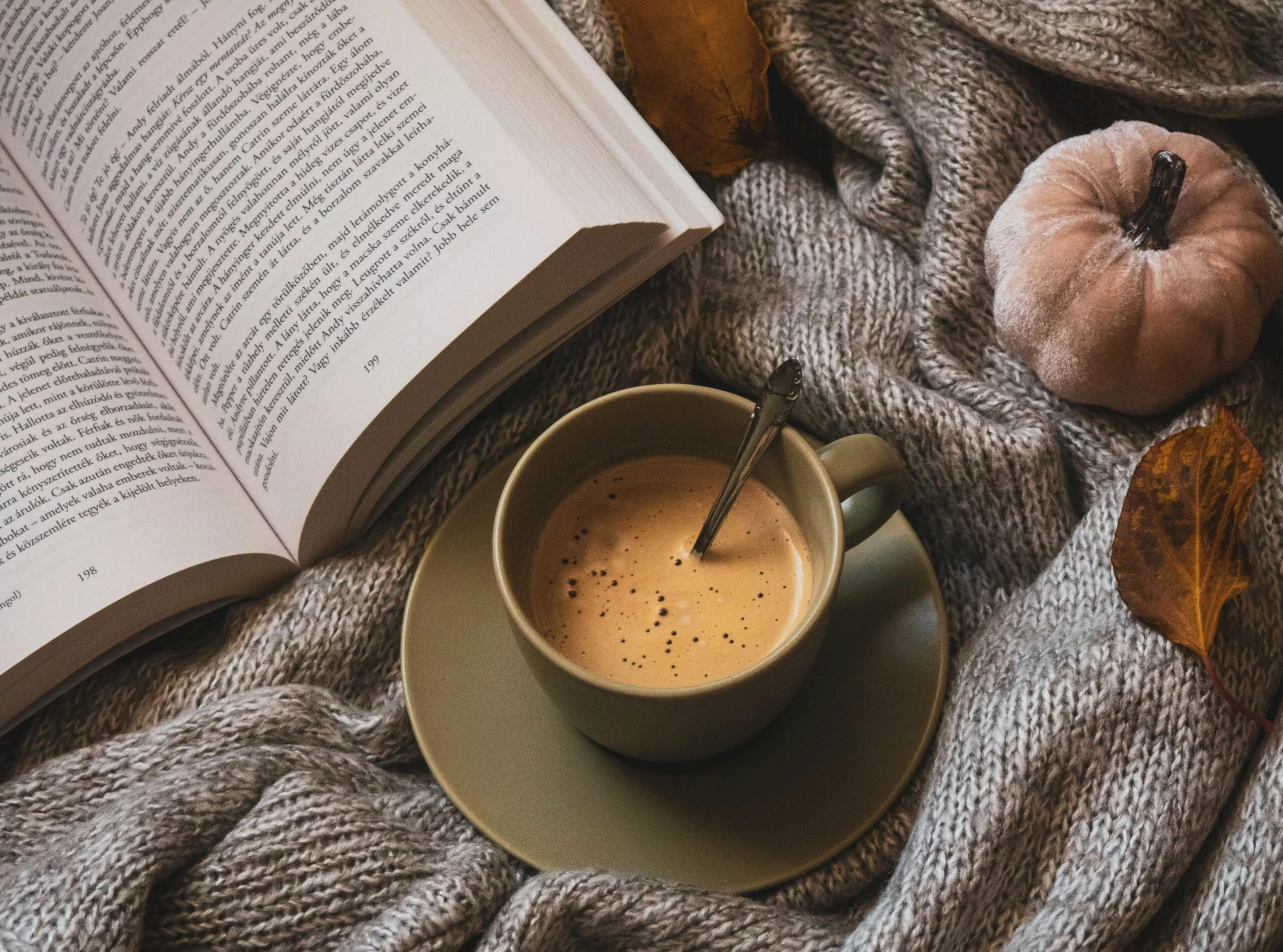 Tasse de café sur un lit avec un livre sur un plaid